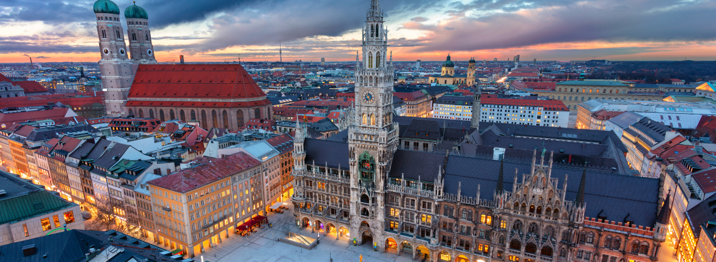 Blick auf Münchens Marienplatz bei Sonnenuntergang, mit dem Neuen Rathaus und der Frauenkirche im Hintergrund.