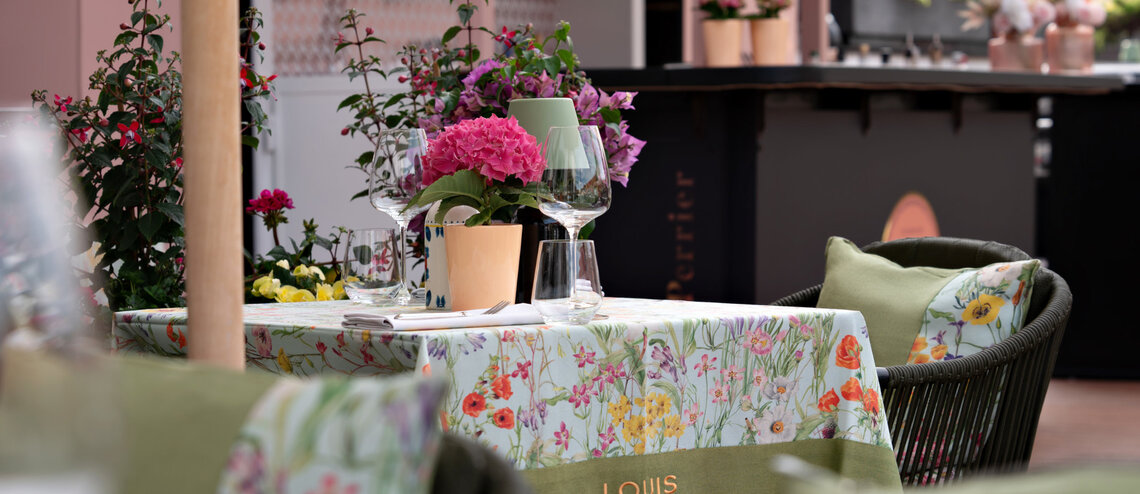 Tisch auf der Dachterrasse mit Weingläsern und Blumen.