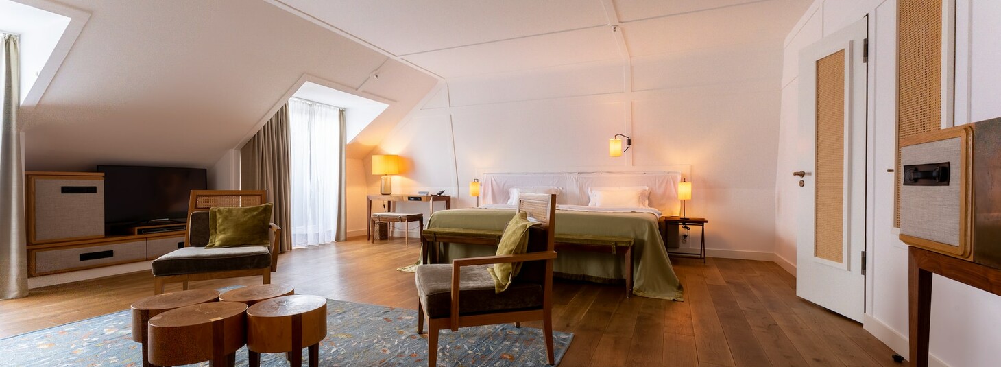 Helles, modernes Hotelzimmer mit Doppelbett, Sitzbereich, Holzboden und Dachschrägen im LOUIS Hotel München.