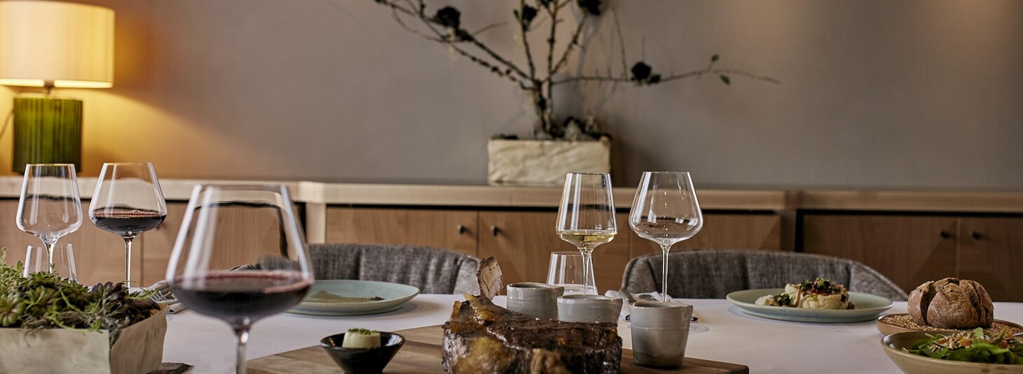 Eleganter Tisch im LOUIS Hotel, gedeckt mit Wein, Geschirr und feinen Speisen in stilvollem Ambiente.