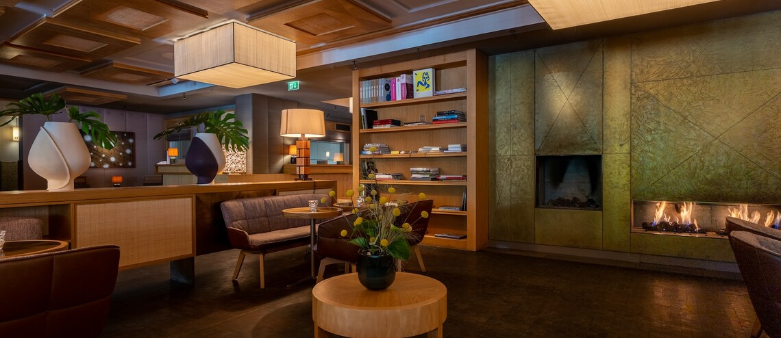 Gemütliche Lounge im LOUIS Hotel München mit Kamin, modernen Möbeln und stilvoller Beleuchtung.