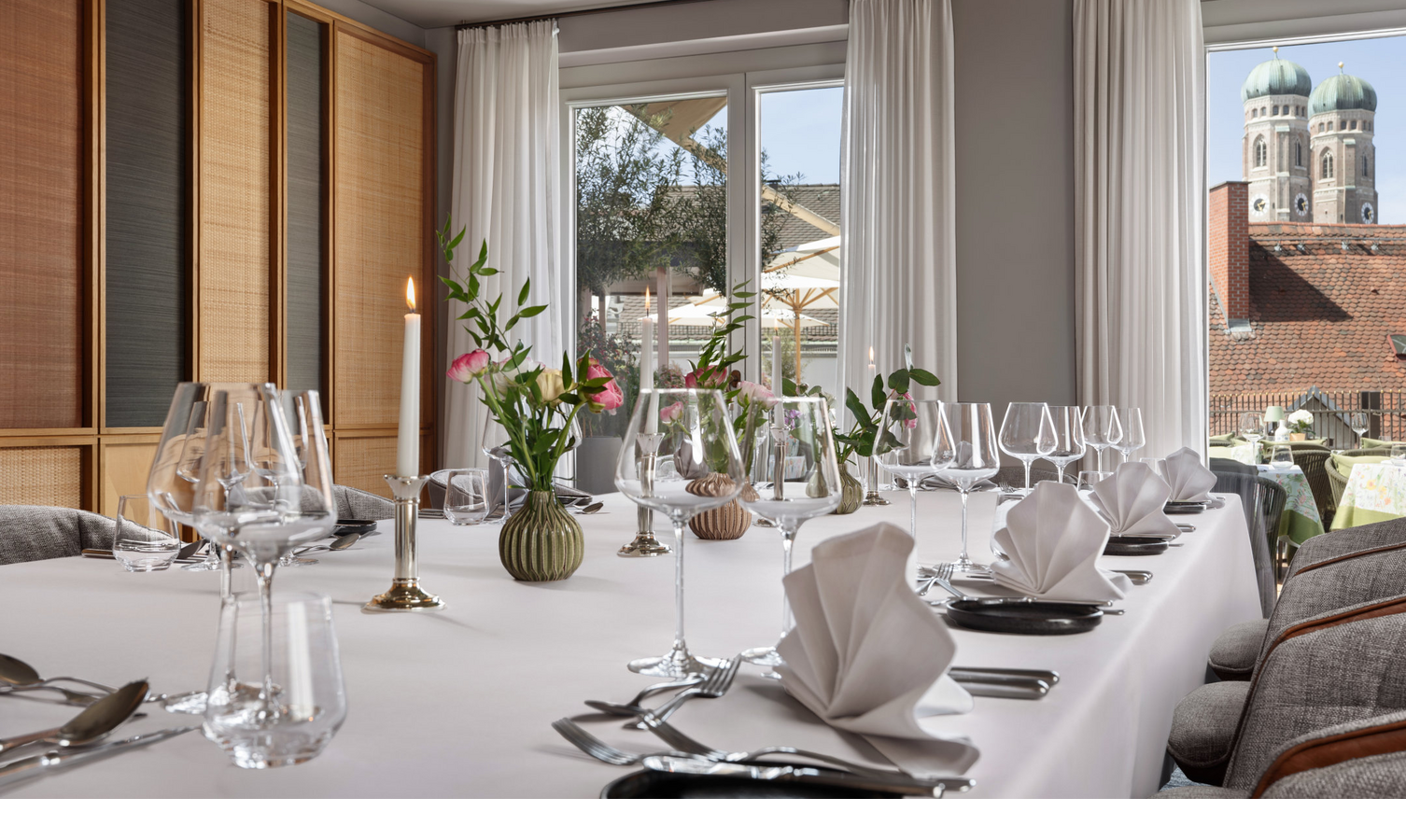 A dining table laid with a white tablecloth, napkins and flowers.