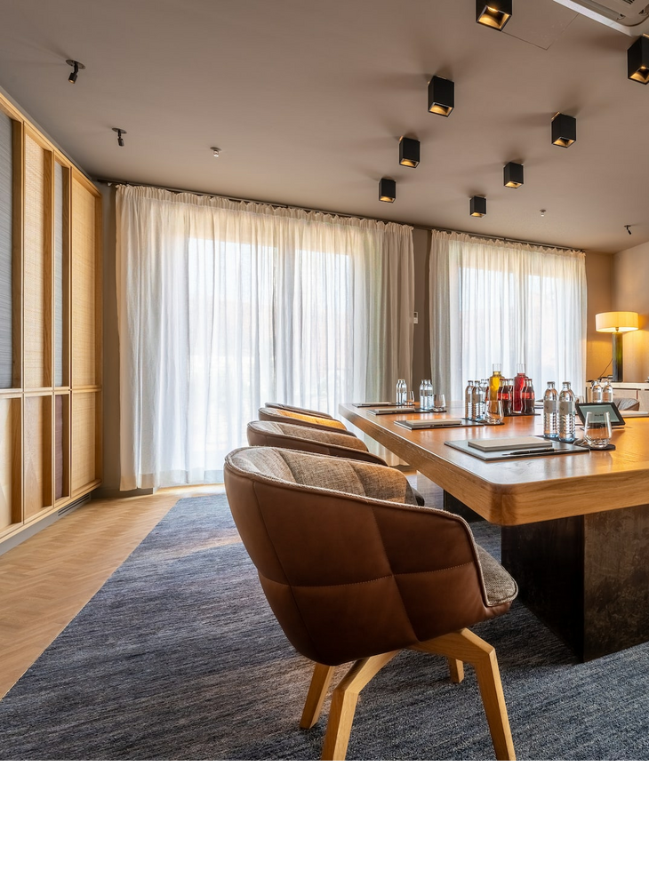 Modern conference room in the LOUIS Hotel Munich with a large wooden table, stylish chairs and natural light.