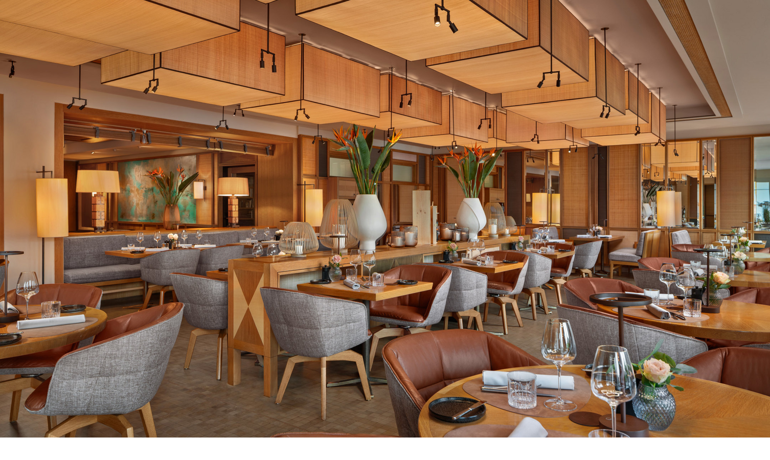 Elegantes Restaurant im LOUIS Hotel München mit stilvollen Holztischen, gemütlichen Sesseln und warmem Lichtambiente.