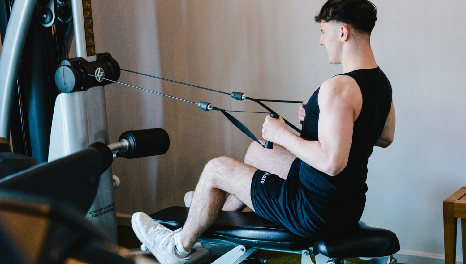 Person trainiert an Fitnessgerät im LOUIS Hotel München. Moderner Fitnessraum mit Krafttrainingsmöglichkeiten.
