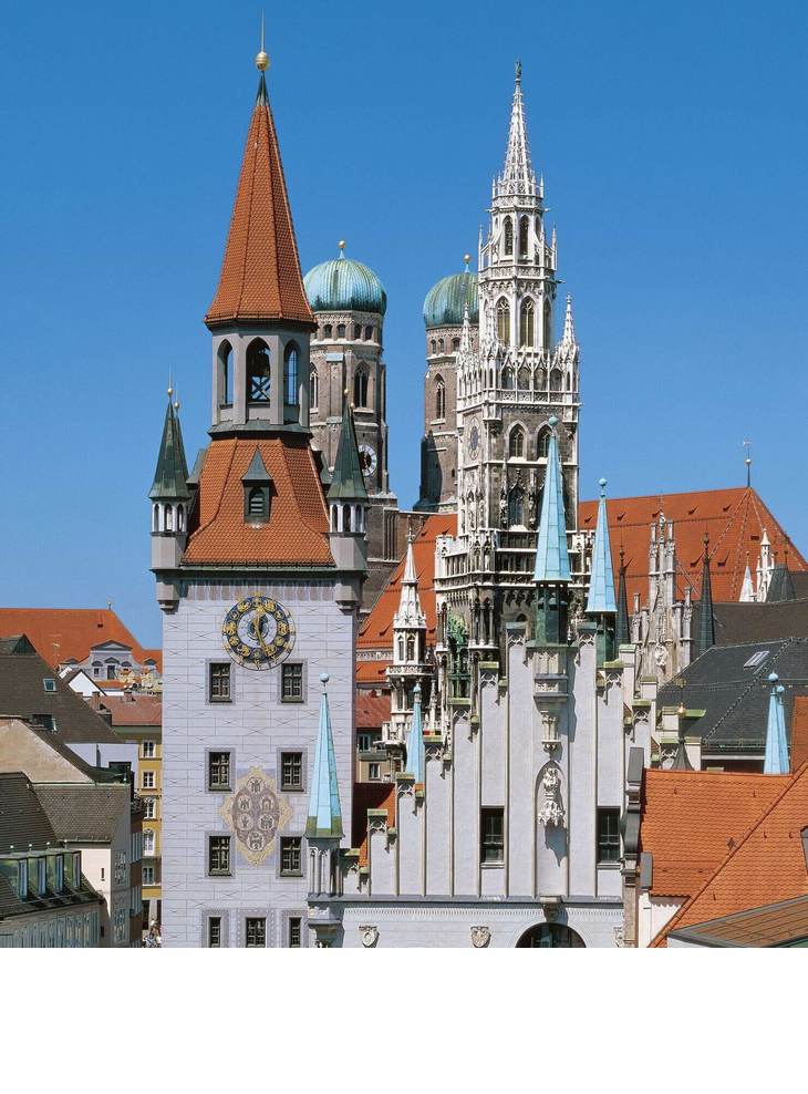Blick auf Münchens Altstadt mit historischen Türmen und roten Dächern vor klarem, blauem Himmel.