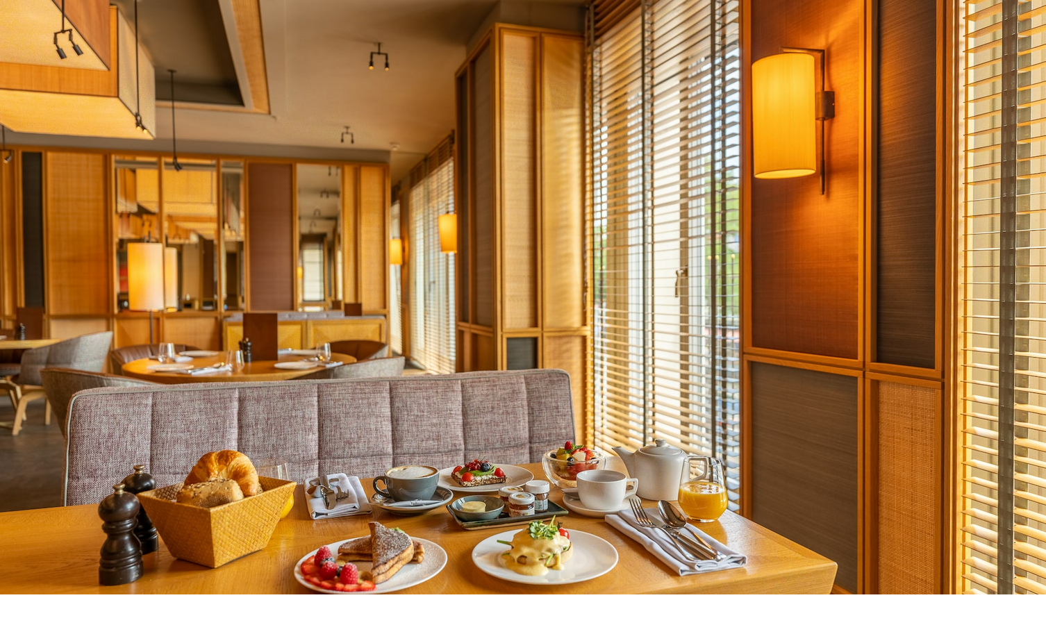 Cozy hotel restaurant with a laid breakfast table, wooden furniture and warm lighting.