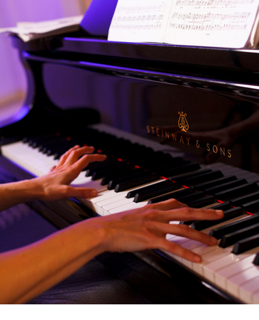 Hands playing the piano, sheet music on the piano, elegant atmosphere.