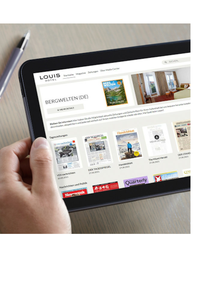 Person hält ein Tablet mit einer Hotelwebseite, daneben eine Tasse Kaffee auf einem Tisch.