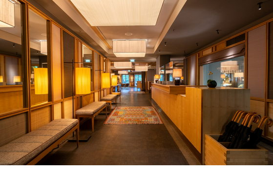 Elegante Hotel-Lobby mit Holzwänden, warmem Licht, Sitzbänken und Teppich im LOUIS Hotel München.