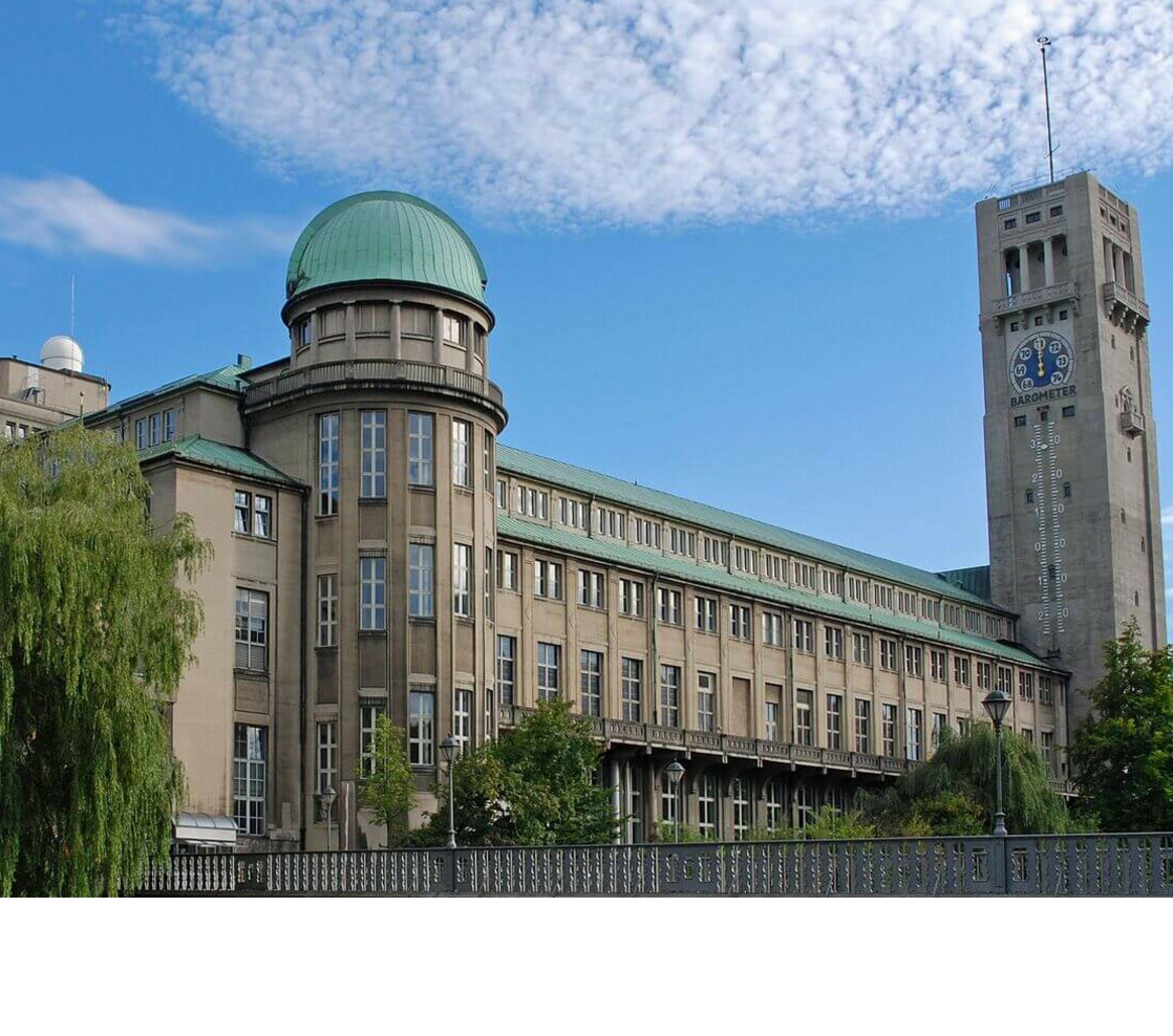 Historic building with green domed roof and tower clock against a blue sky.