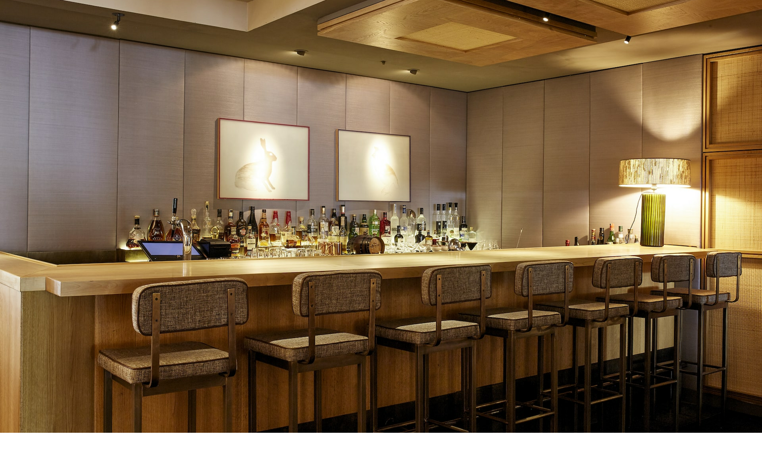 Elegante Hotelbar mit hölzerner Theke, Barhockern und stilvoller Beleuchtung im LOUIS Hotel München.
