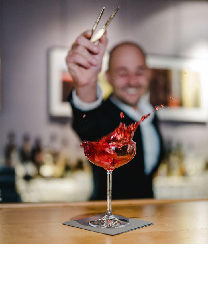 A bartender at the LOUIS Hotel Munich mixes a sparkling red cocktail.
